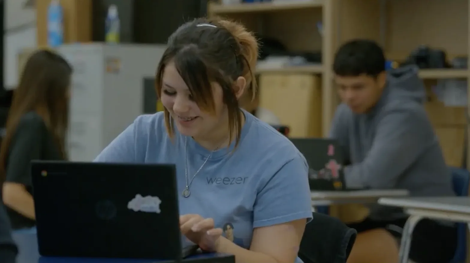 Student completing classwork on a laptop in a classroom