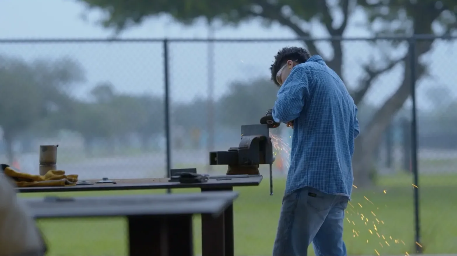 Student learning metalworking outdoors with an instructor