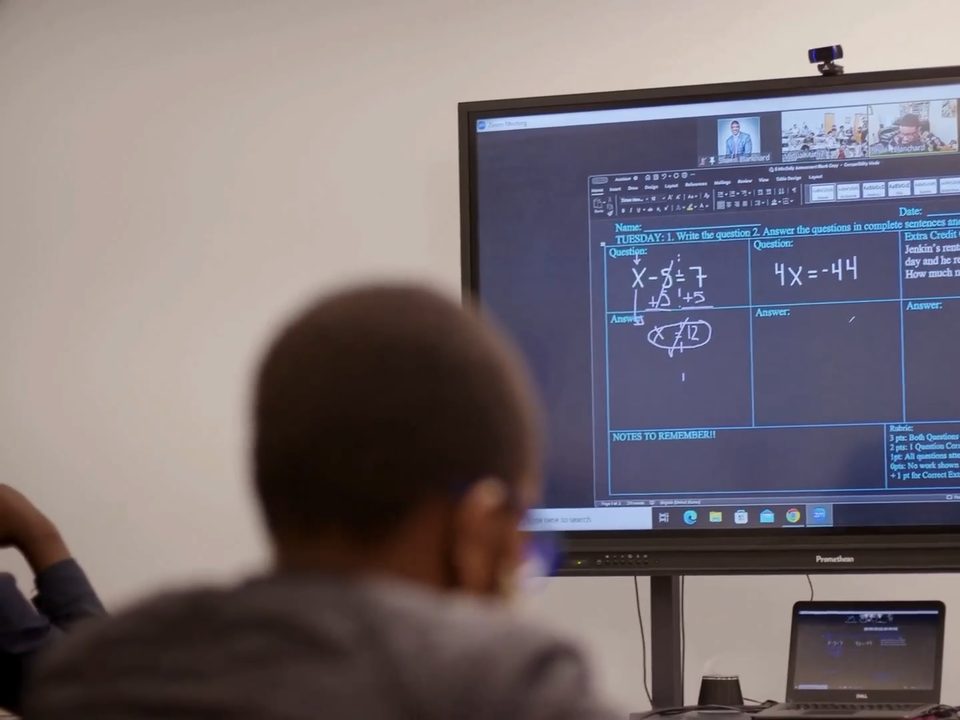 A student follows a live tutor's math lesson on the classroom display, as in Fullmind high-dosage tutoring.